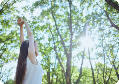 森の中で女性が背中を伸ばし、ノビノビとしている様子